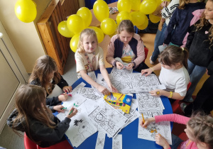 Uczennice siedzą przy stoliku i malują kolorowanki relaksacyjne