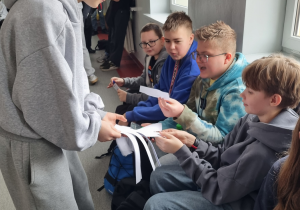 Uczeń rozdaje kolegom karteczki z zadaniami