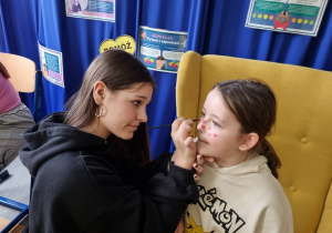 Uczennica maluje twarz koleżance