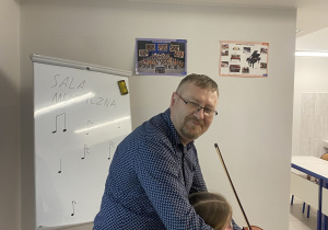 Uczennica gra na skrzypcach z pomocą nauczyciela