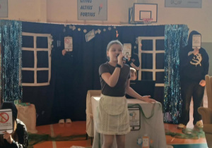 Uczennica stoi z mikrofonem