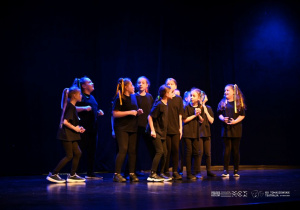 Grupa dziewczynek biega po scenie