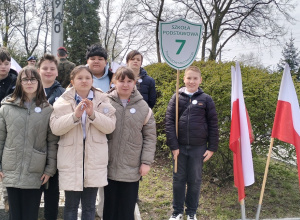Uczniowie z tarczą szkoły pozują do zdjęcia.