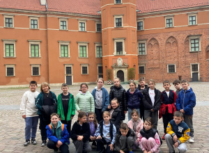 Grupa uczniów pozuje na dziedzińcu Zamku Królewskiego w Warszawie.
