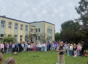 Pani dyrektor, nauczyciele, pracownicy szkoły i uczniowie stoją przed budynkiem szkolnym