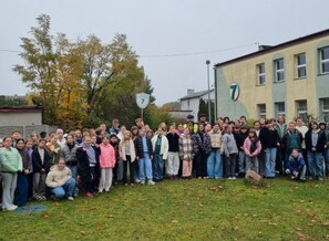 Grupa uczniów stoi przed szkołą